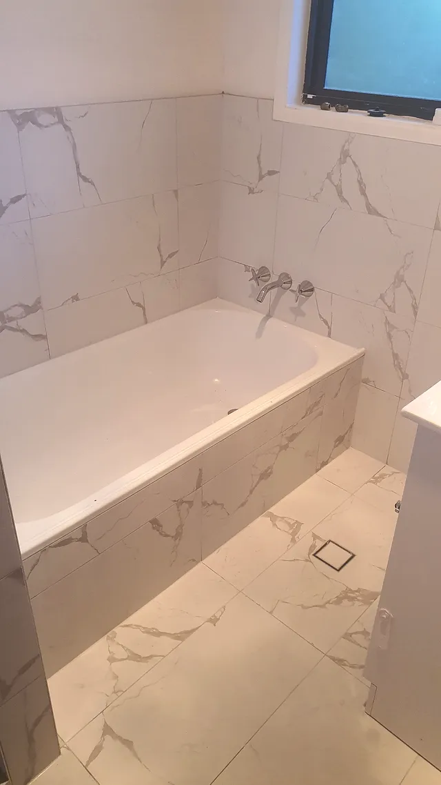 Built-in bath with marble-look tiled surround and matching floor tiles