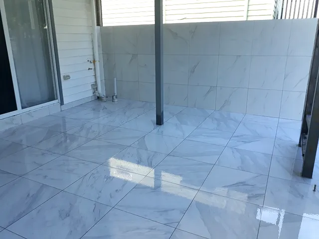 Glossy marble-look floor tiles laid in a diagonal pattern on a covered alfresco area