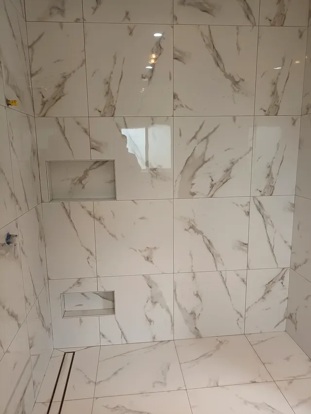 Shower with marble-look wall tiles, a recessed niche and a linear floor drain